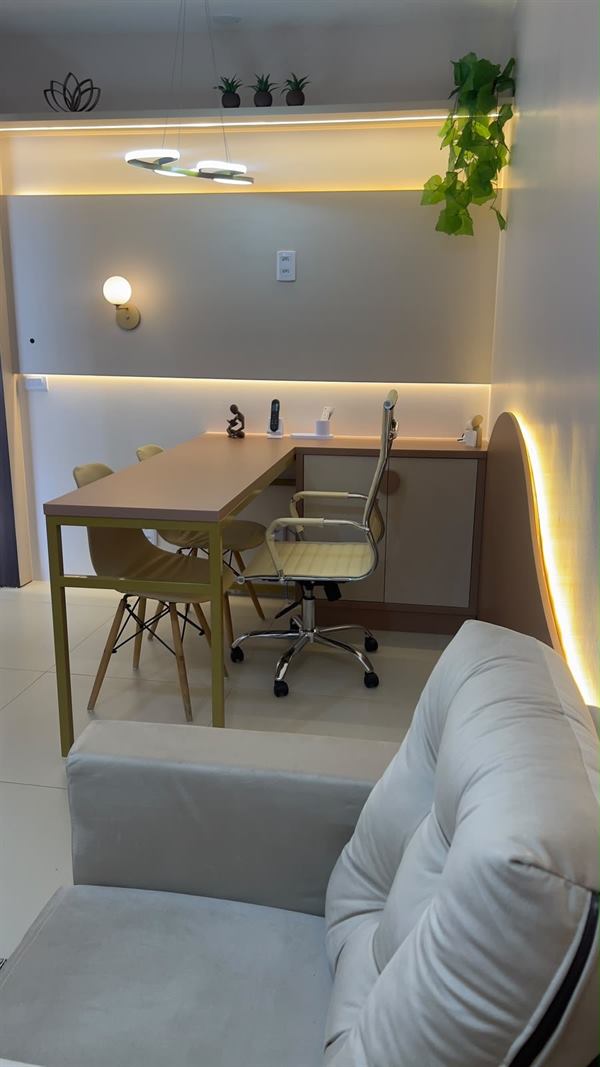 Mesa em L com cadeira de escritório e luz indireta