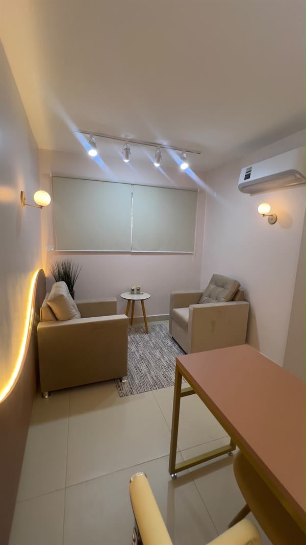 Visão geral da sala, com poltronas, mesa lateral e ar-condicionado
